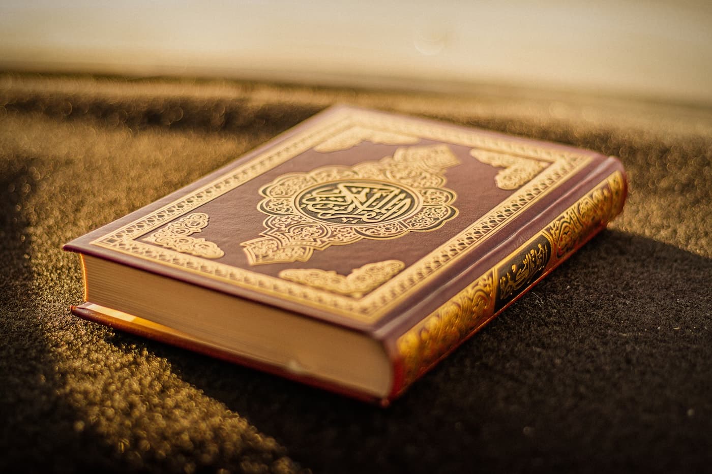 A Qur’an with gold calligraphy under warm light.