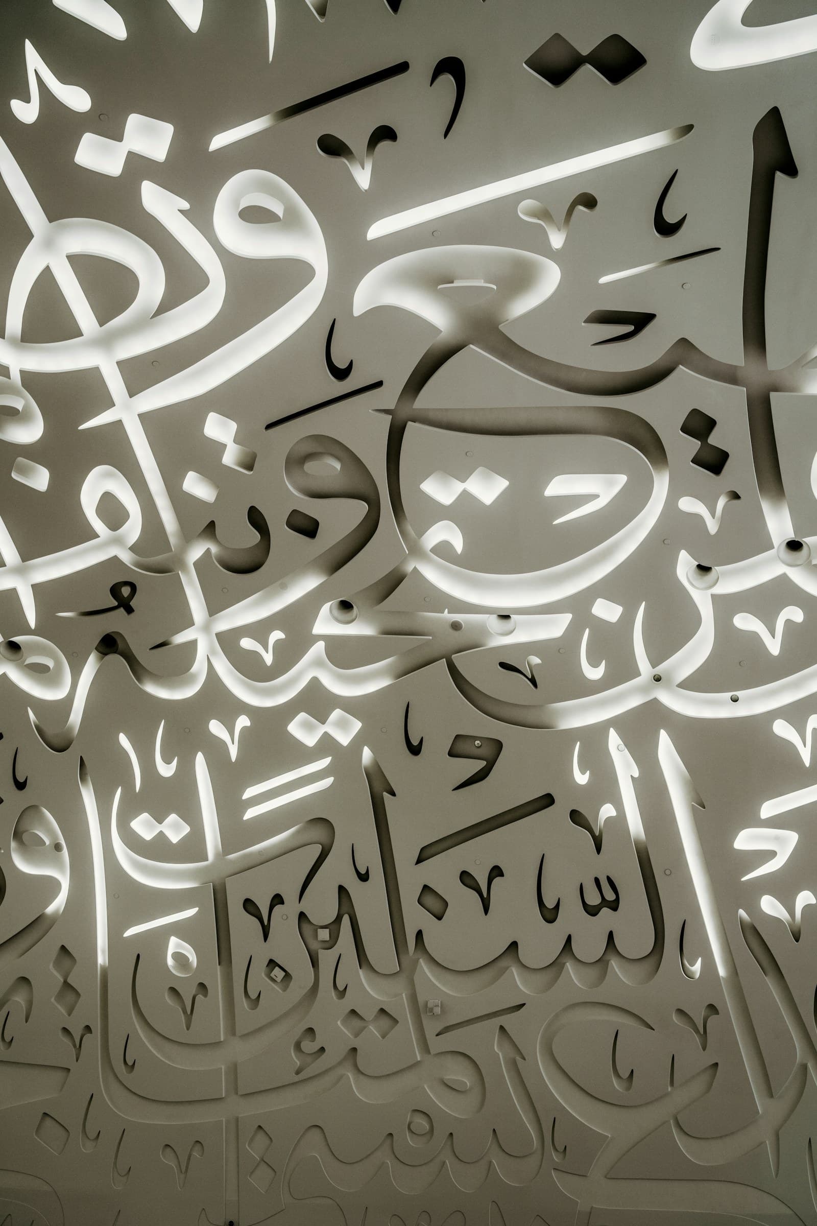 Backlit Arabic calligraphy cut into a modern architectural panel.